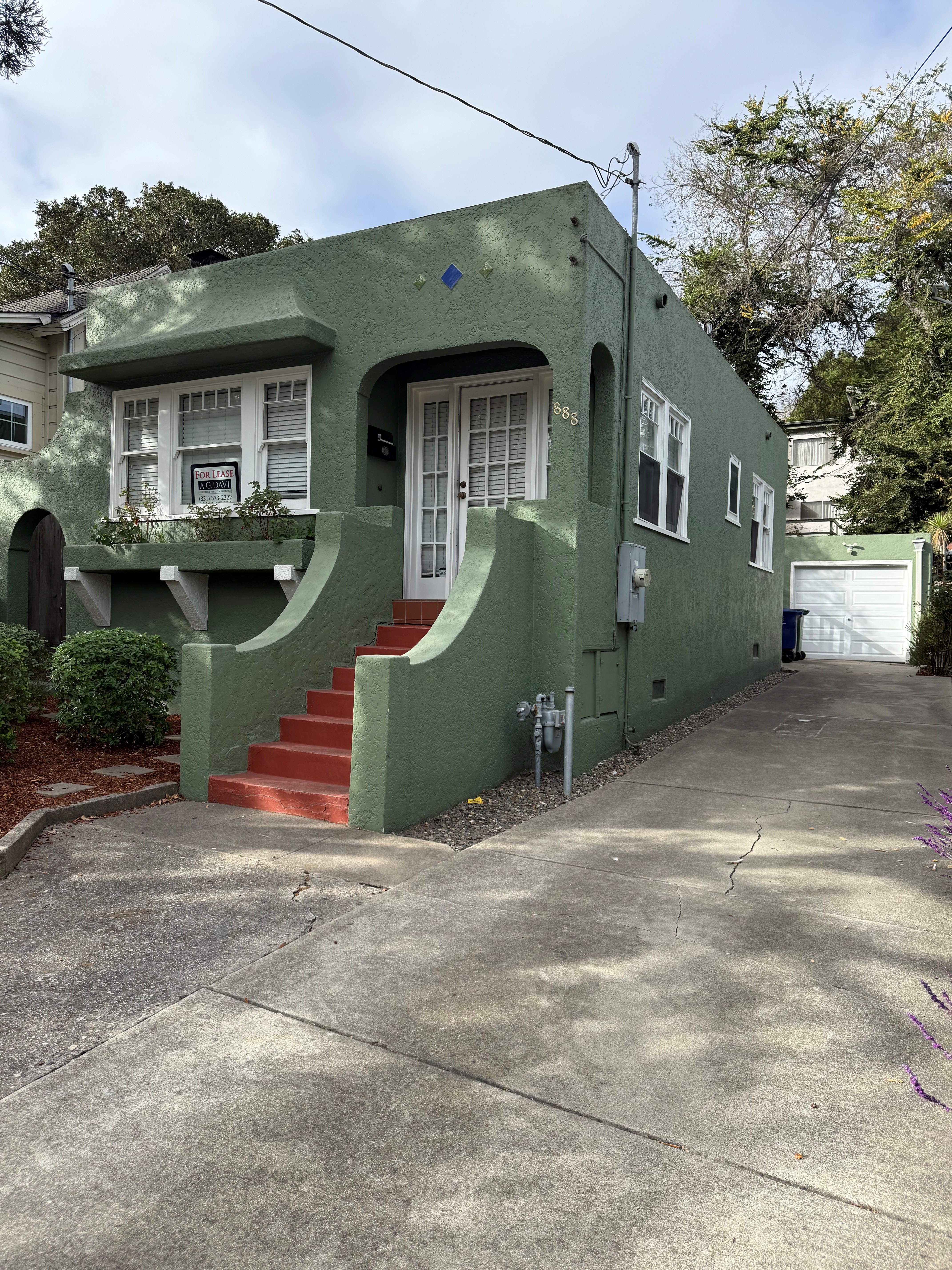 A green house with a white door and windows.